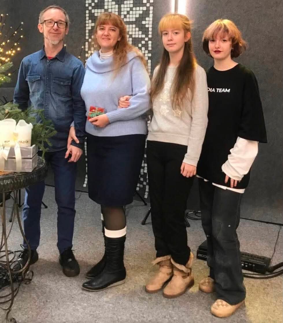 Sveta with her husband and their two daughters beside a Christmas tree